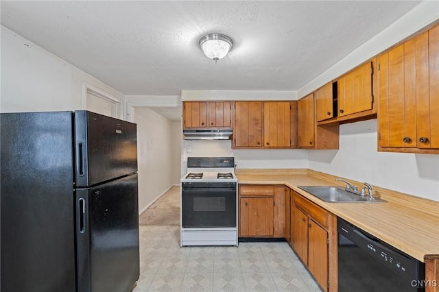 kitchen featuring light floors, under cabinet range hood, light countertops, black appliances, and a sink