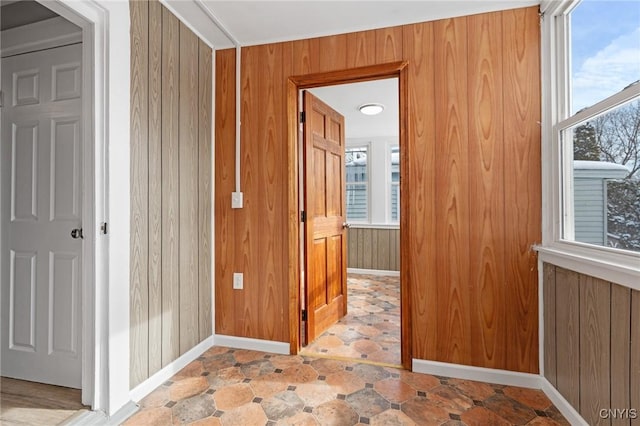 corridor featuring wood walls and baseboards