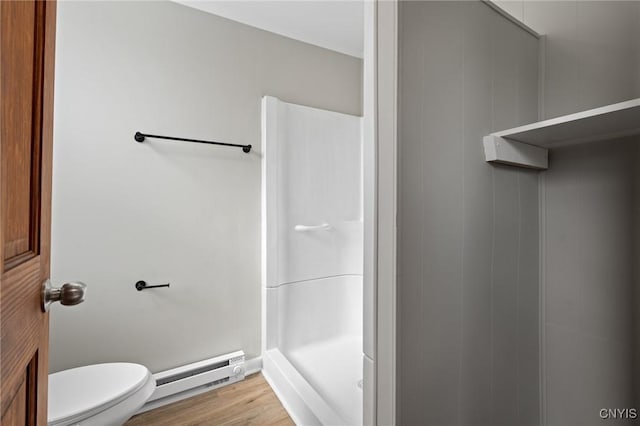 bathroom featuring a stall shower, a baseboard radiator, toilet, and wood finished floors