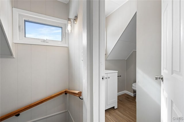 half bath with toilet, wood finished floors, and vanity