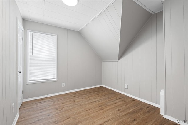 additional living space with vaulted ceiling, baseboards, and wood finished floors