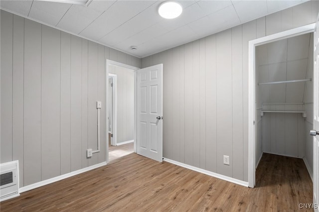 unfurnished bedroom with a closet, wood finished floors, a walk in closet, and baseboards