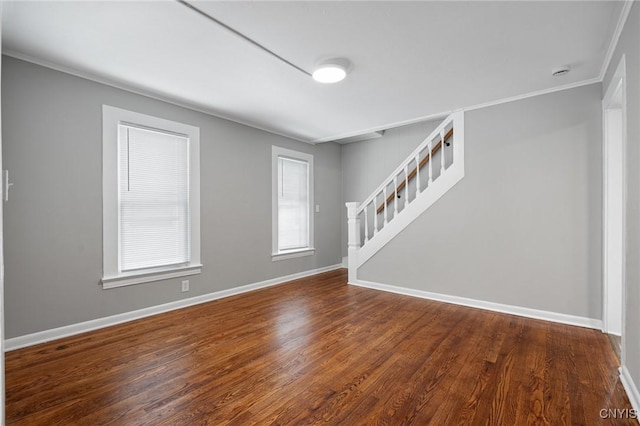 empty room featuring crown molding, stairway, baseboards, and wood finished floors