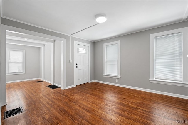 foyer entrance featuring a healthy amount of sunlight, visible vents, baseboards, and wood finished floors