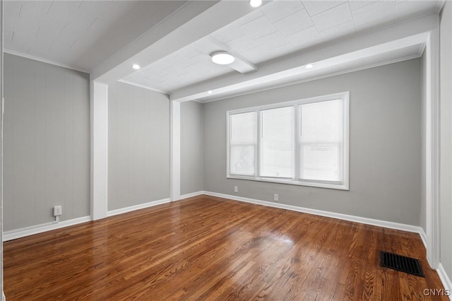 empty room with ornamental molding, visible vents, baseboards, and wood finished floors