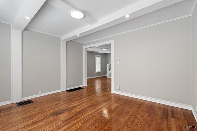 empty room featuring baseboards, visible vents, wood finished floors, and ornamental molding