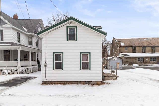 snow covered house featuring a porch