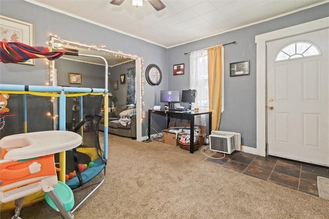 interior space featuring a ceiling fan, dark colored carpet, crown molding, and baseboards