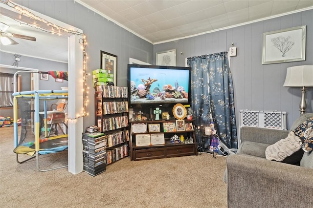 living area featuring ornamental molding, carpet, and a ceiling fan