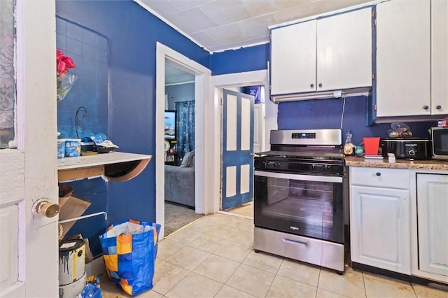 kitchen with white cabinets, light tile patterned floors, stainless steel appliances, and light countertops