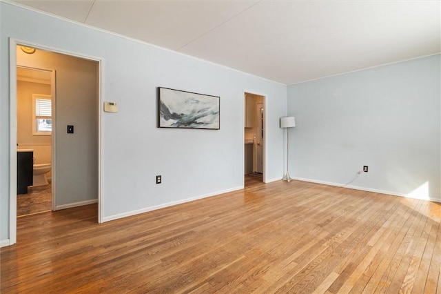 empty room with baseboards, crown molding, and hardwood / wood-style floors