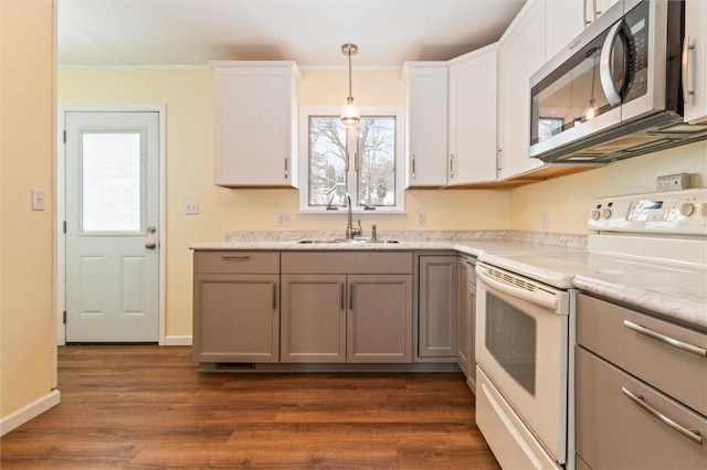 kitchen with white electric range oven, stainless steel microwave, white cabinetry, pendant lighting, and a sink