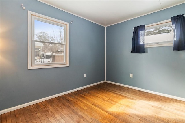 spare room featuring crown molding, baseboards, and hardwood / wood-style flooring