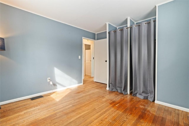 spare room with crown molding, baseboards, visible vents, and light wood-style floors