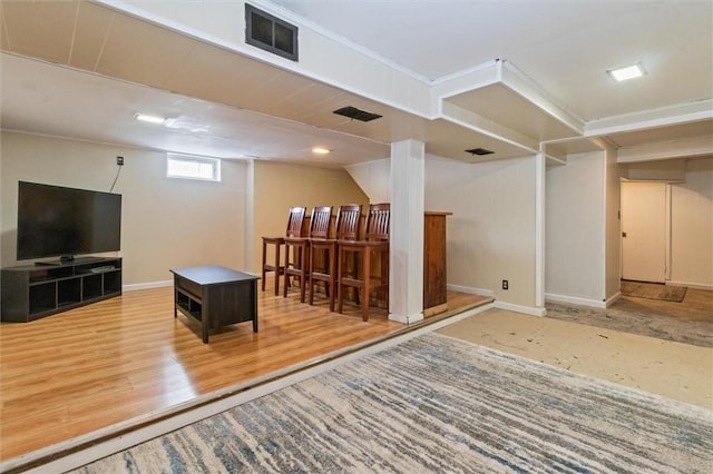 below grade area with a dry bar, wood finished floors, visible vents, and baseboards