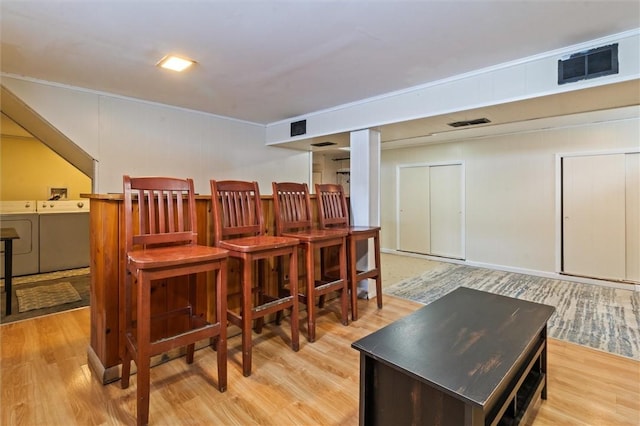 bar featuring light wood-style flooring, visible vents, and separate washer and dryer