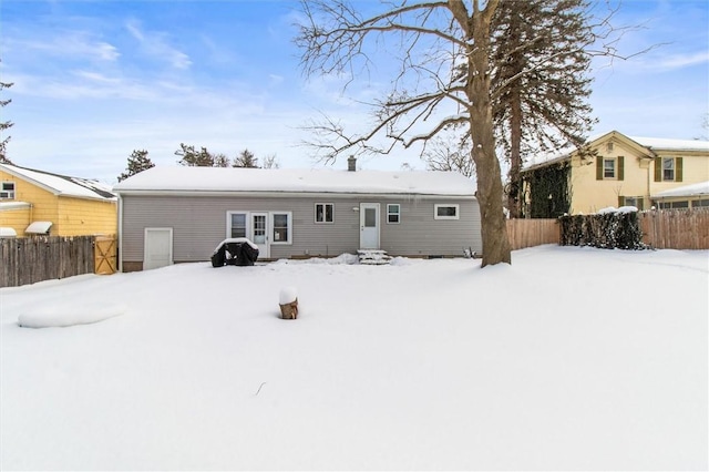 snow covered back of property with entry steps and fence