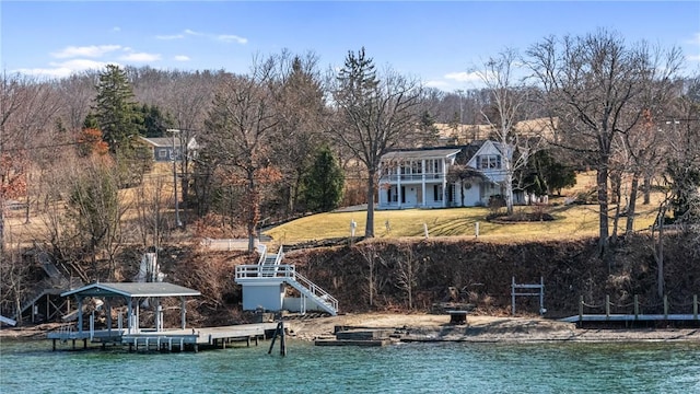exterior space featuring stairs, a lawn, and a water view