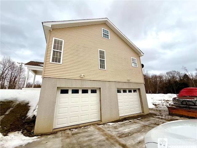 view of snow covered exterior with stucco siding and a garage