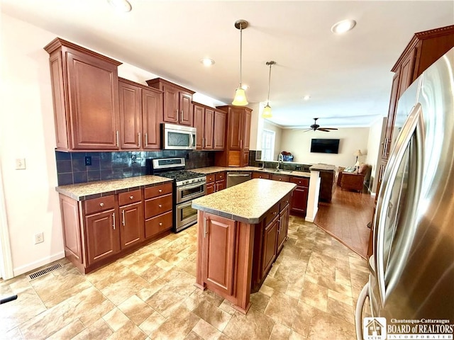 kitchen featuring backsplash, a kitchen island, light countertops, a peninsula, and stainless steel appliances