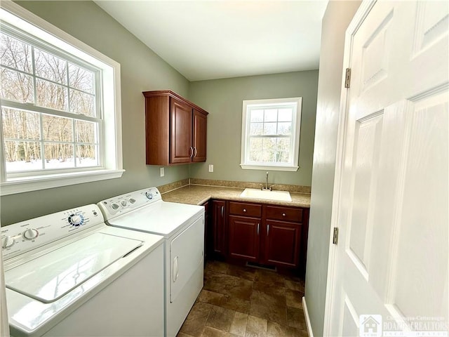 laundry area with washing machine and dryer, cabinet space, stone finish flooring, and a sink