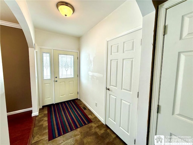 entrance foyer with arched walkways, visible vents, and baseboards