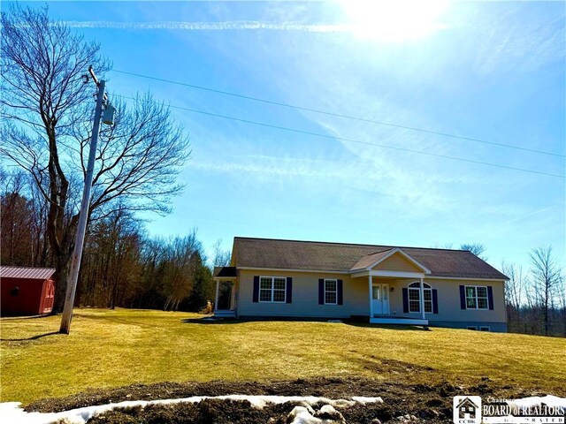 ranch-style home with a storage unit, an outbuilding, covered porch, and a front lawn