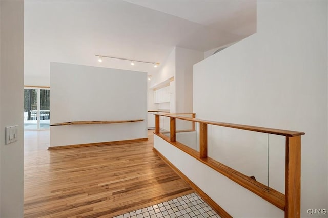 hall with rail lighting, light wood-style flooring, and baseboards