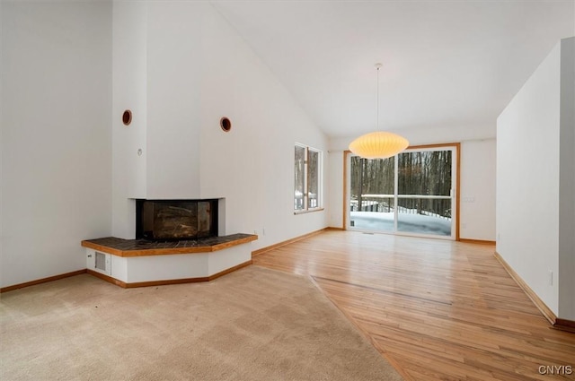 unfurnished living room featuring high vaulted ceiling, baseboards, and light wood finished floors