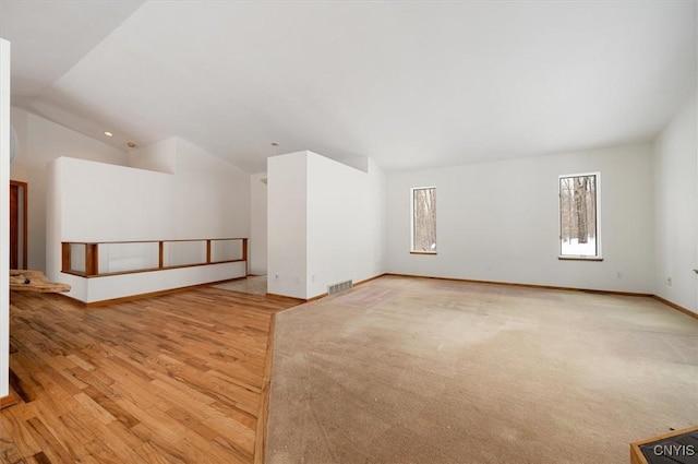 additional living space featuring baseboards, visible vents, and vaulted ceiling