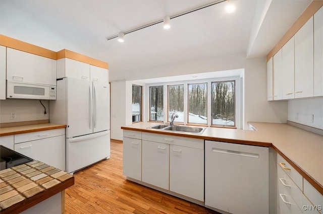 kitchen with light countertops, white appliances, a sink, and white cabinetry