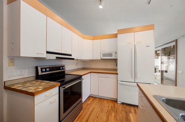 kitchen featuring white appliances, light wood-style flooring, white cabinets, and under cabinet range hood