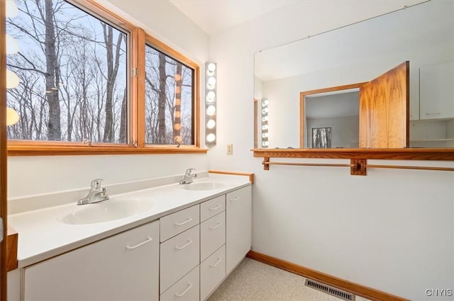 full bath featuring double vanity, a sink, visible vents, and baseboards