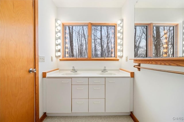 full bath featuring a sink, baseboards, and double vanity