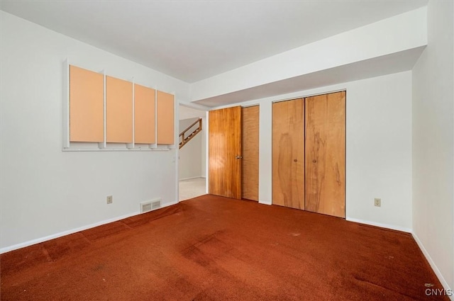 carpeted empty room featuring baseboards and visible vents