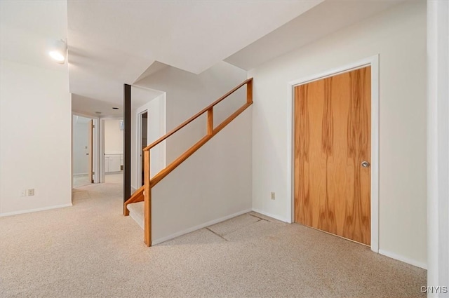 interior space featuring baseboards, stairway, and light colored carpet