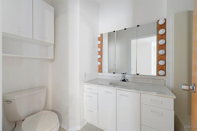 bathroom with toilet, vanity, and baseboards