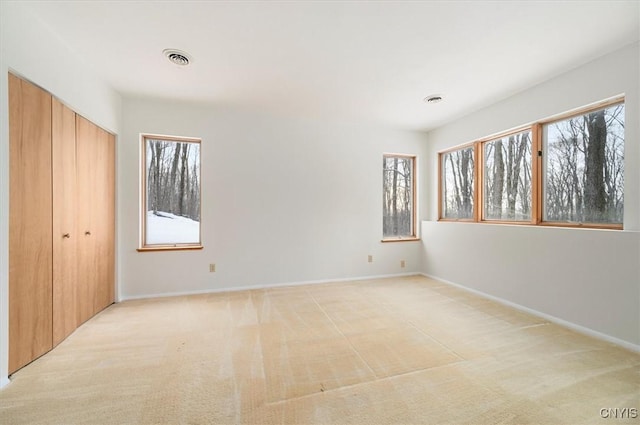 unfurnished bedroom featuring light colored carpet, visible vents, and baseboards