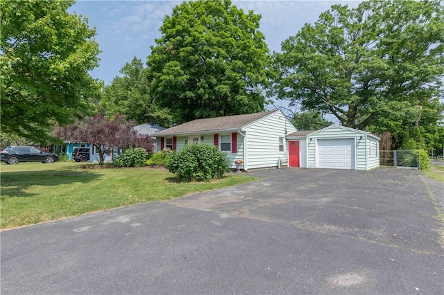 single story home featuring driveway, a garage, an outbuilding, fence, and a front yard