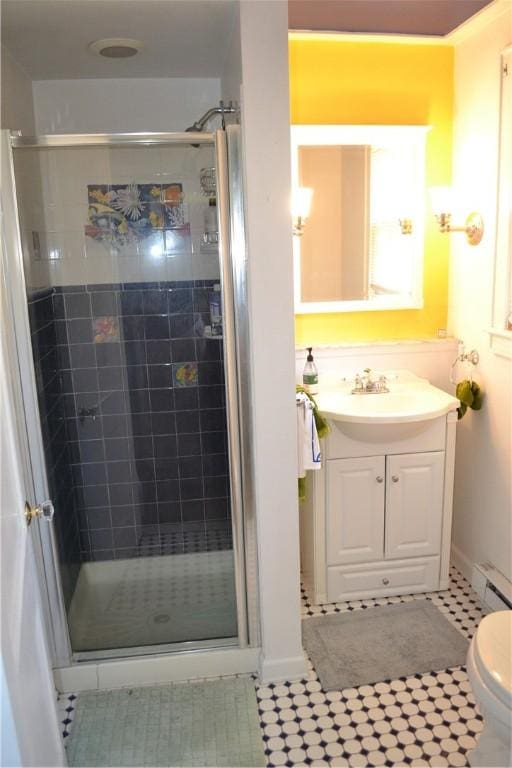 bathroom featuring toilet, a stall shower, baseboard heating, and vanity