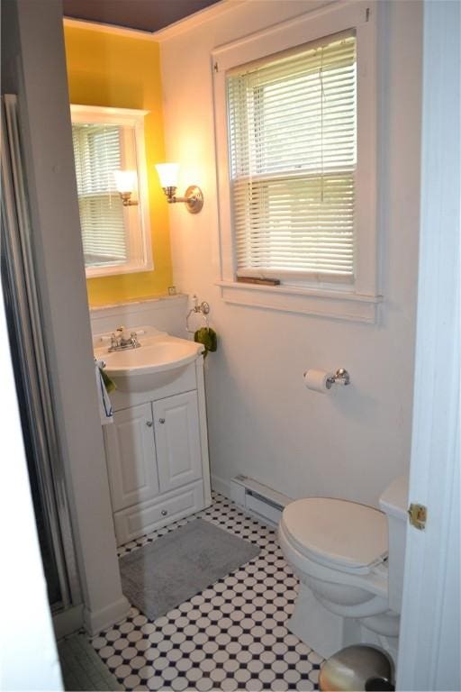 half bath with toilet, baseboard heating, and vanity