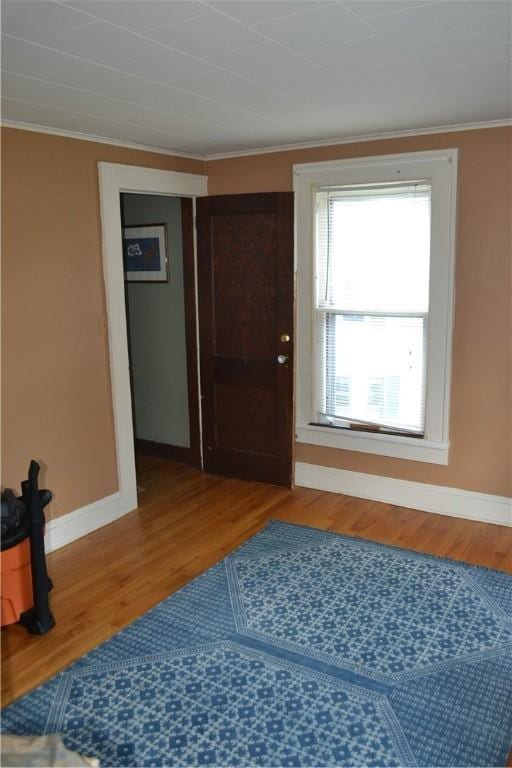 interior space with crown molding, baseboards, and wood finished floors