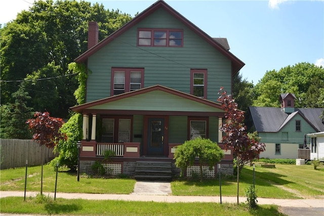 traditional style home with covered porch, a front lawn, and fence