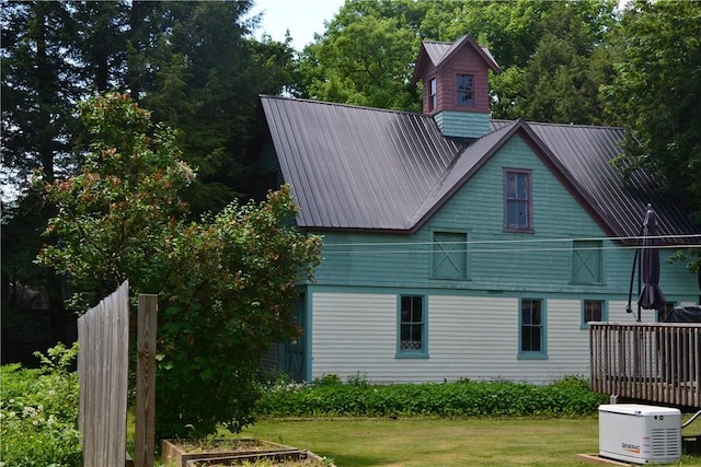 back of house with metal roof and a lawn