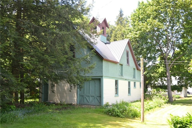 view of home's exterior with a garage, metal roof, and a lawn