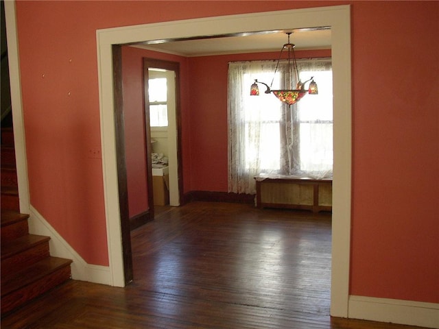 unfurnished dining area with stairs, baseboards, and wood finished floors