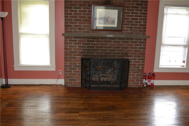 unfurnished living room featuring a fireplace, baseboards, and wood finished floors