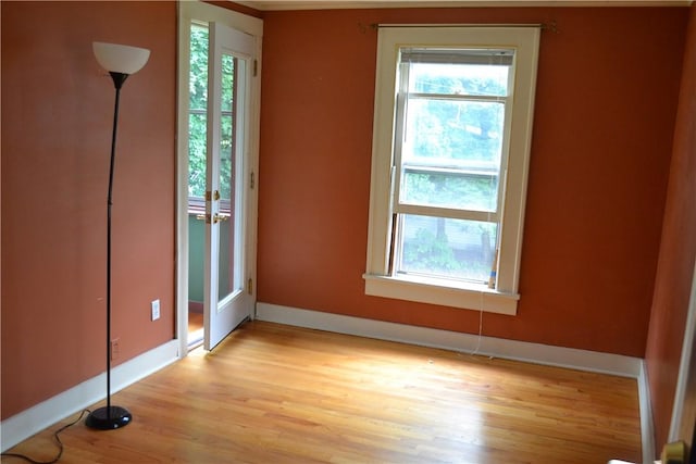 unfurnished bedroom with baseboards, multiple windows, and light wood finished floors