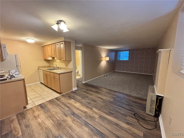 kitchen featuring light brown cabinets, white appliances, a sink, light wood-style floors, and light countertops