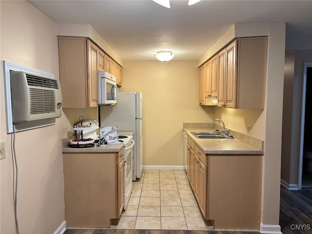 kitchen featuring white appliances, baseboards, a wall unit AC, light brown cabinetry, and a sink